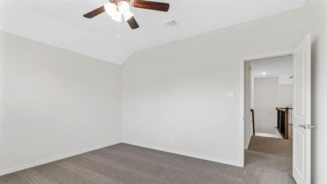 Carpeted room featuring a sloped ceiling, ceiling fan with integrated lighting, and a neutral wall color