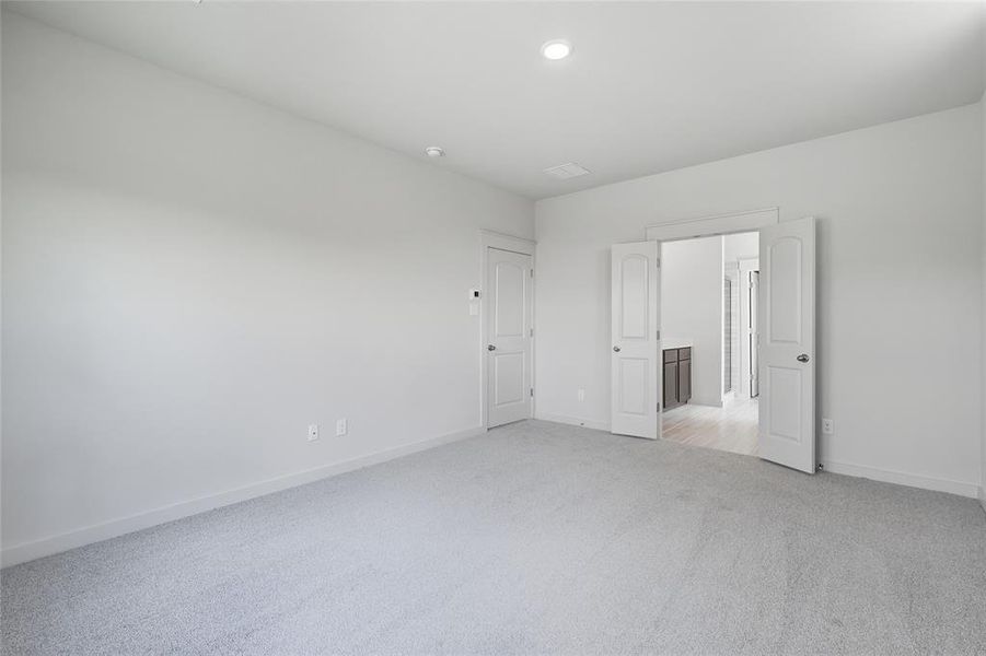 Unfurnished bedroom with light colored carpet and recessed lighting Unfurnished bedroom with light colored carpet and recessed lighting