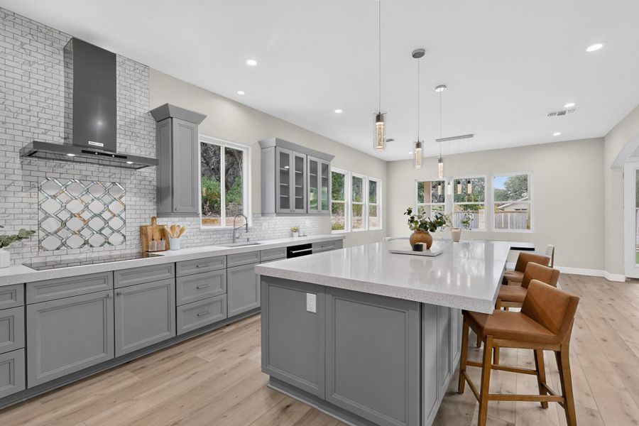 Sleek gray cabinetry and a large central island anchor this open-concept kitchen space.