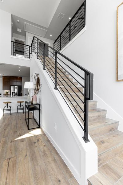 Stairs with wood-type flooring, a towering ceiling, and recessed lighting