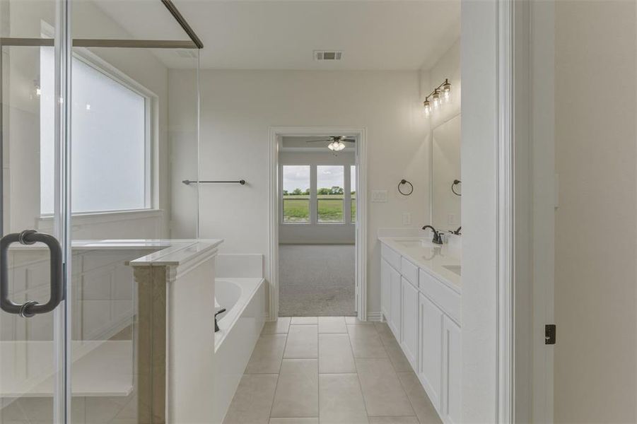 Bathroom featuring a glass-enclosed shower, a built-in bathtub, a double vanity with white cabinetry, light-colored tile flooring, and a frosted window Bathroom featuring a glass-enclosed shower, a built-in bathtub, a double vanity with white cabinetry, light-colored tile flooring, and a frosted window