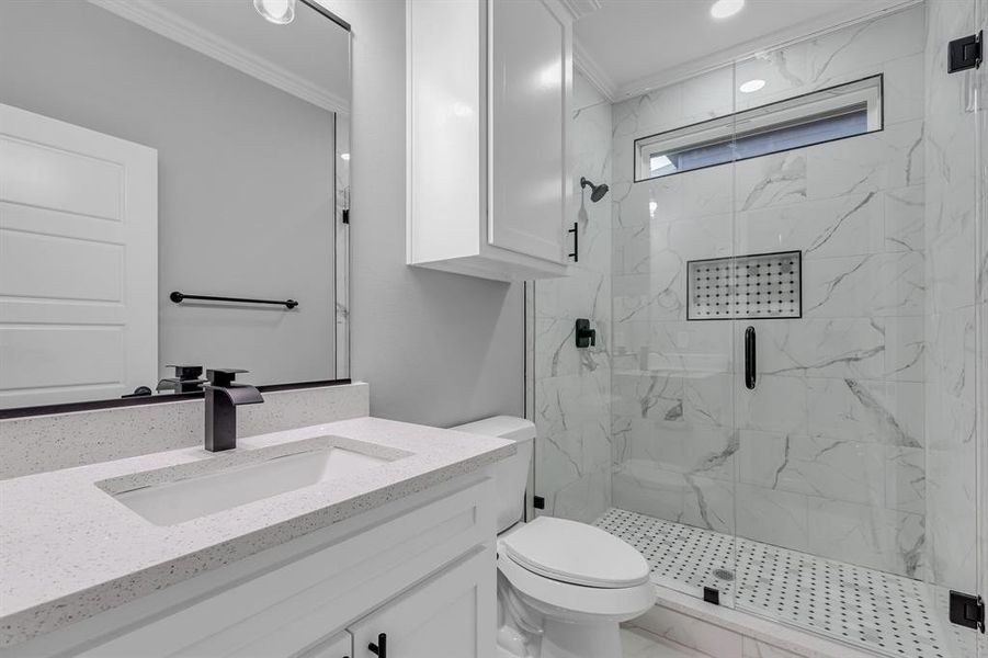 Bathroom with toilet, vanity, a shower with shower door, and ornamental molding