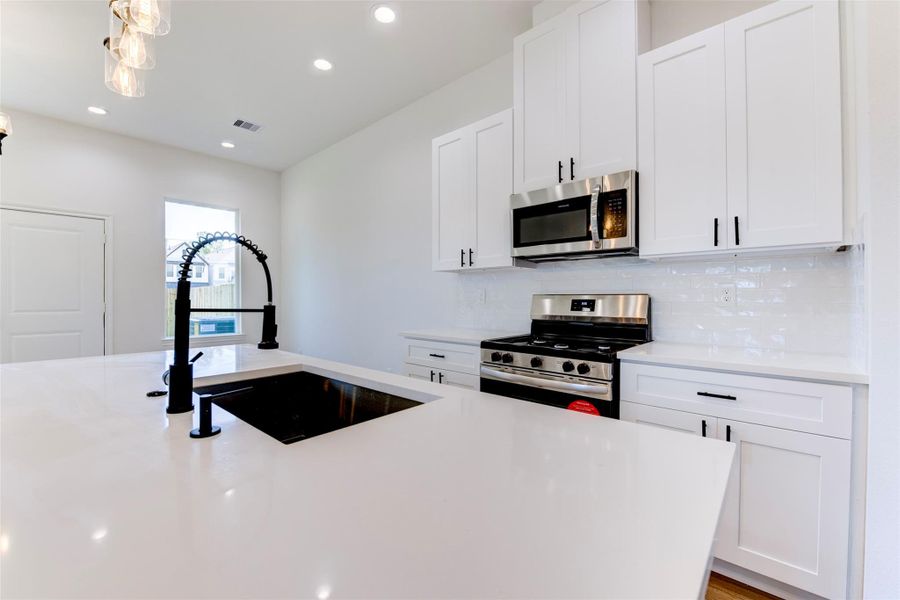 Spacious island with deep sink and gooseneck faucet, ideal for prep and entertaining.