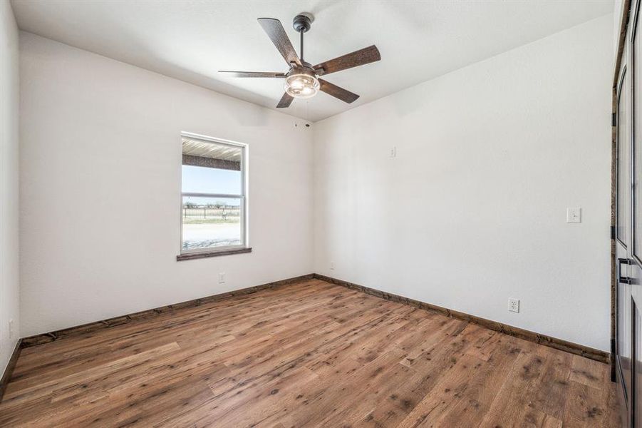Unfurnished room featuring baseboards, wood finished floors, and a ceiling fan