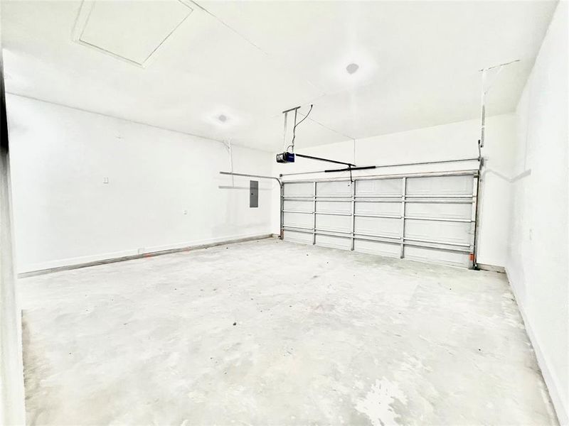 Garage with electric panel, baseboards, and a garage door opener