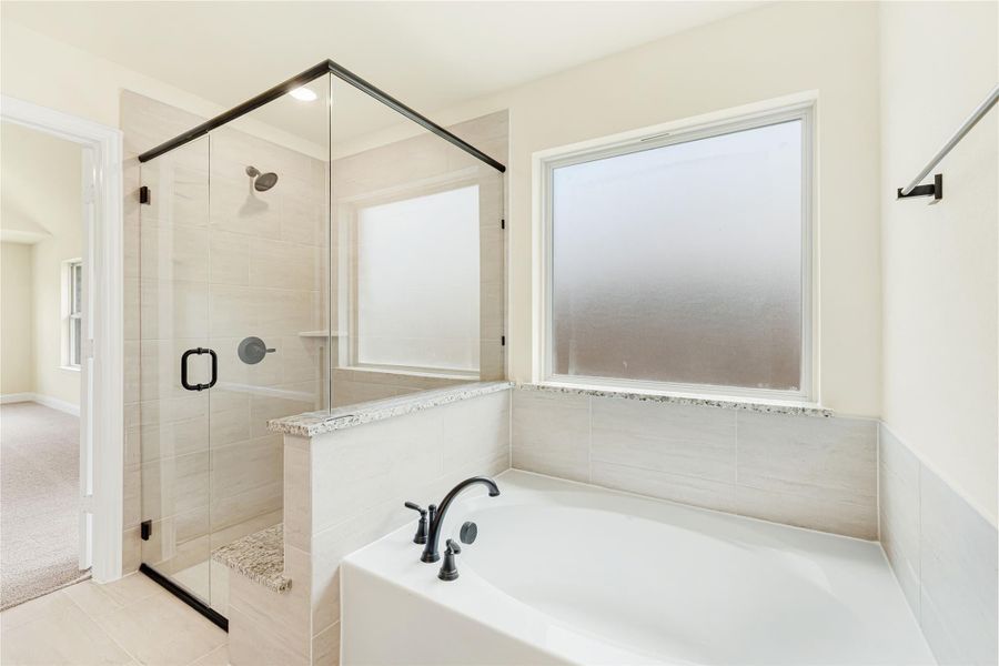 Bathroom with soaking tub, glass-enclosed tile shower, black fixtures, and frosted window Bathroom with soaking tub, glass-enclosed tile shower, black fixtures, and frosted window
