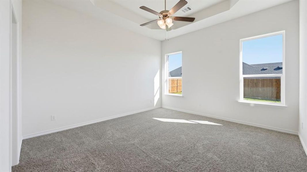 Unfurnished room featuring a tray ceiling, carpet flooring, and a ceiling fan Unfurnished room featuring a tray ceiling, carpet flooring, and a ceiling fan