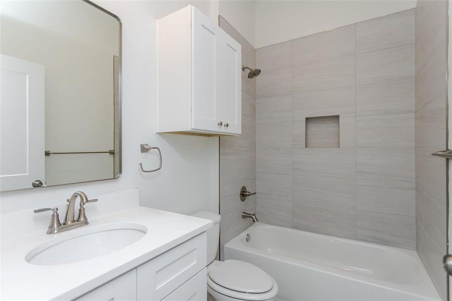 Full bathroom with vanity, tiled shower / bath combo, and toilet