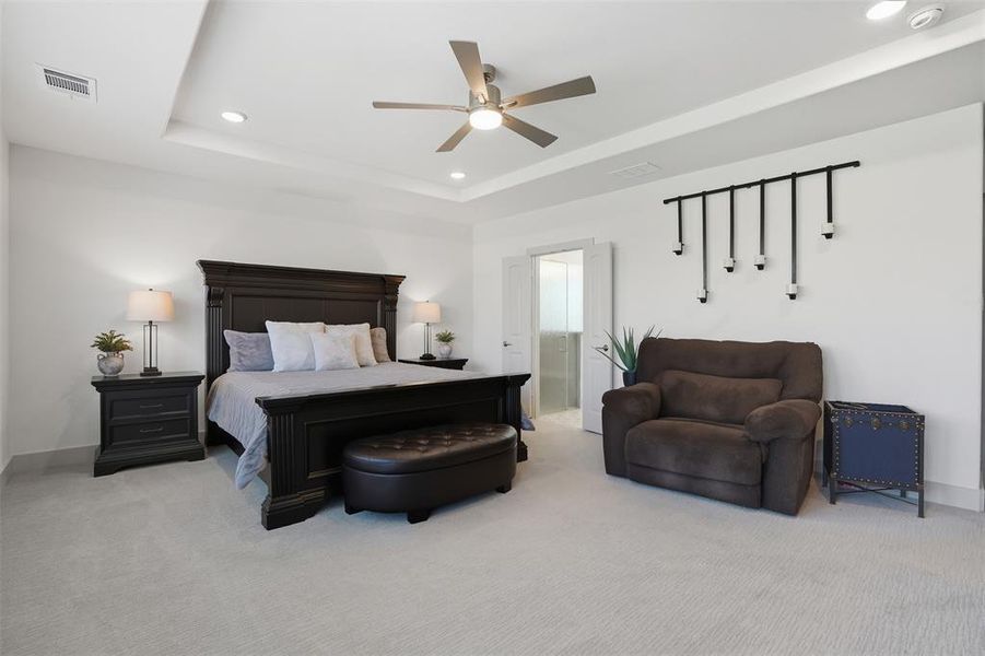 Carpeted bedroom featuring recessed lighting, a raised ceiling, and a ceiling fan Carpeted bedroom featuring recessed lighting, a raised ceiling, and a ceiling fan