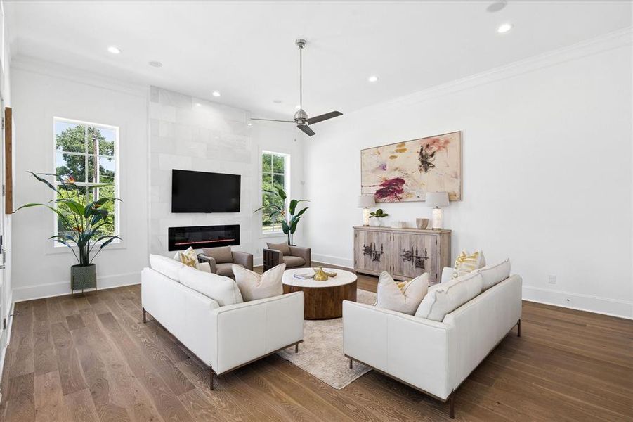 Spacious living area featuring wood-finish flooring, a contemporary fireplace with a stone surround, and an integrated television mount