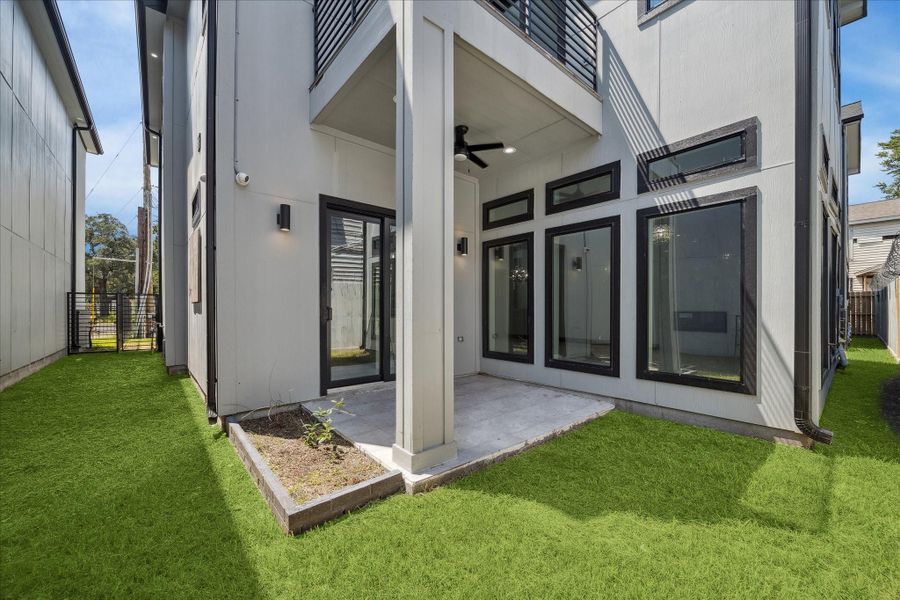 Outdoor dining and relaxation come easy on the shaded patio, complete with a ceiling fan and yard access. Generous windows enhance the connection to the home’s interior spaces.