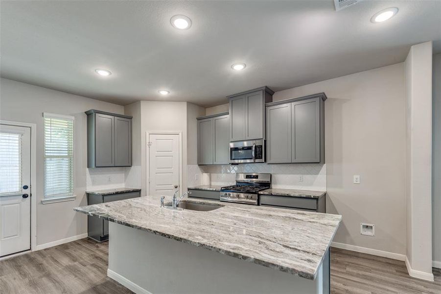 The kitchen boasts a large center island with elegant granite countertops, a gas range, breakfast bar seating, and a spacious pantry for ample storage. The kitchen boasts a large center island with elegant granite countertops, a gas range, breakfast bar seating, and a spacious pantry for ample storage.