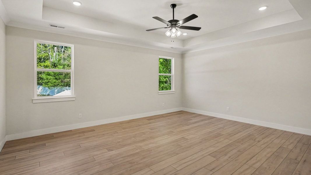 Primary bedroom with tray ceilings and fan Primary bedroom with tray ceilings and fan
