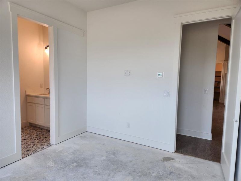 Unfurnished bedroom featuring connected bathroom and sink