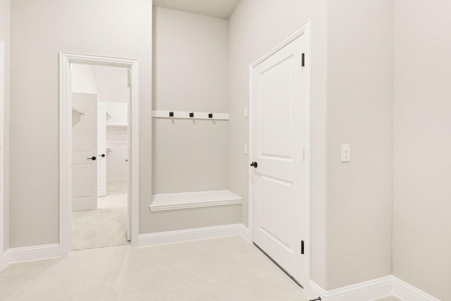 Mudroom entry with wall hooks, built-in bench, and white doors with black hardware Mudroom entry with wall hooks, built-in bench, and white doors with black hardware