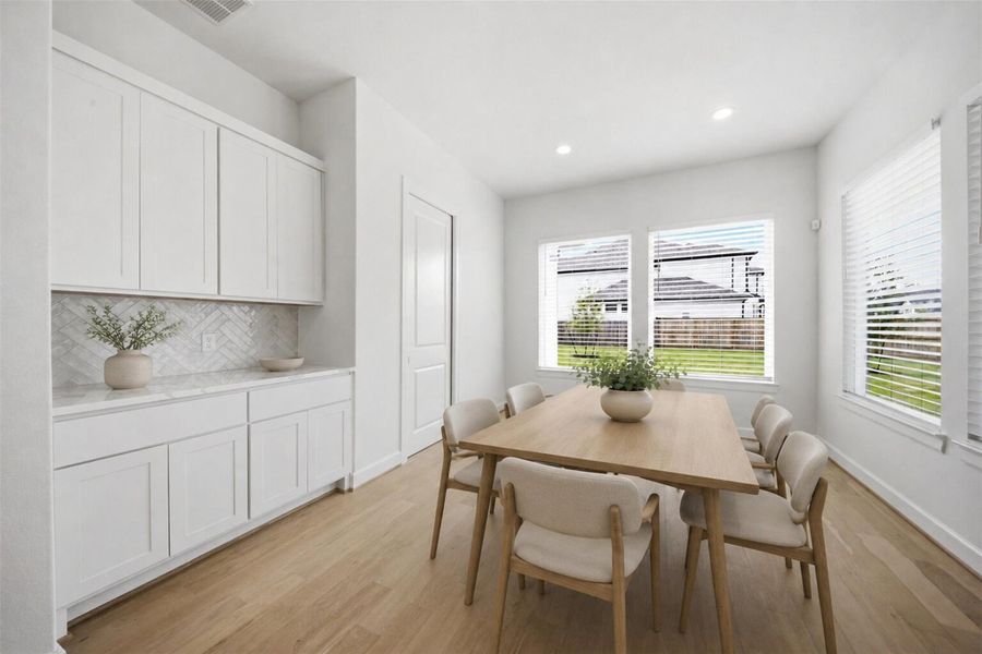 **Virtually Staged** Bright and airy dining space conveniently located adjacent to the kitchen with abundant natural light and built-in serving cabinetry.