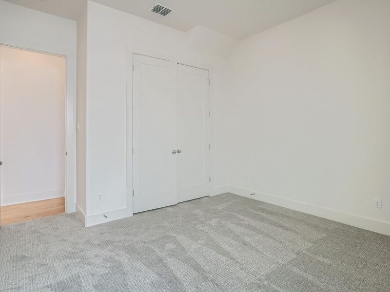 Unfurnished bedroom featuring light carpet and a closet