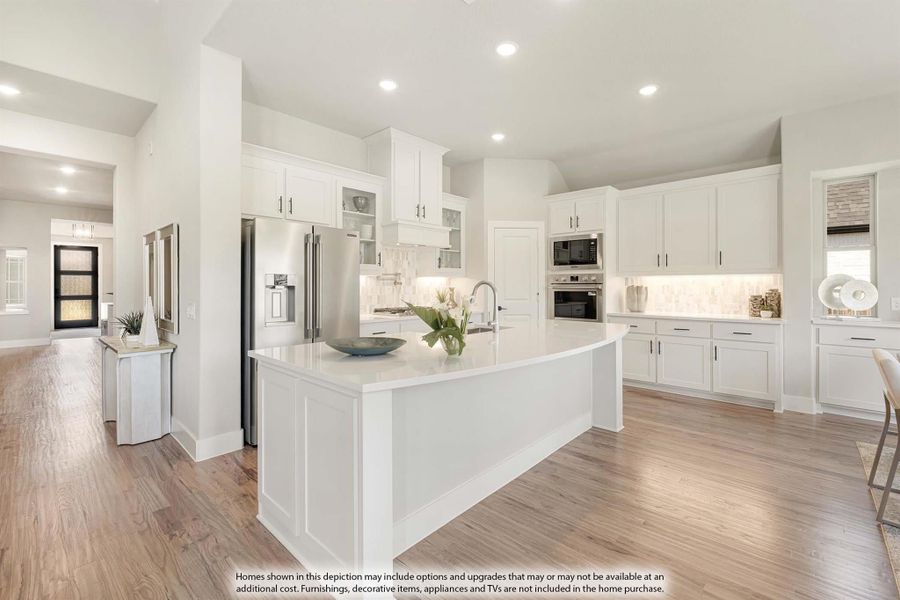 White kitchen with large center island, stainless steel appliances, and light hardwood floors
