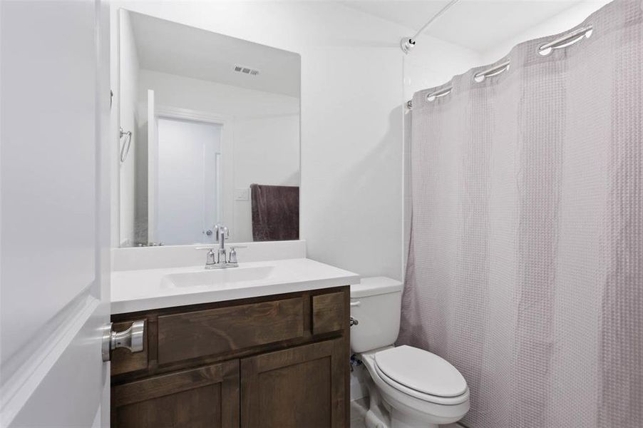 Bathroom featuring a dark wood-finish vanity, white countertop, integrated rectangular sink, and chrome faucet