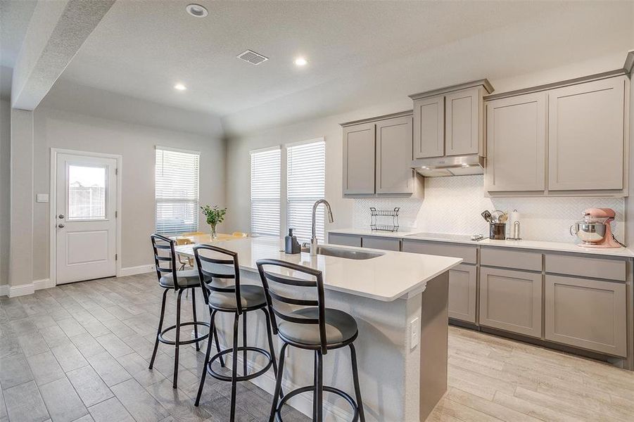 Kitchen with an island with sink and gray cabinets