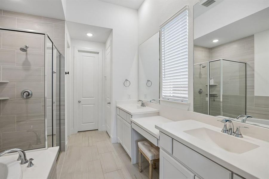 Bathroom featuring a glass-enclosed shower with tile surround, a built-in bathtub, dual vanities with integrated sinks, and neutral-toned flooring