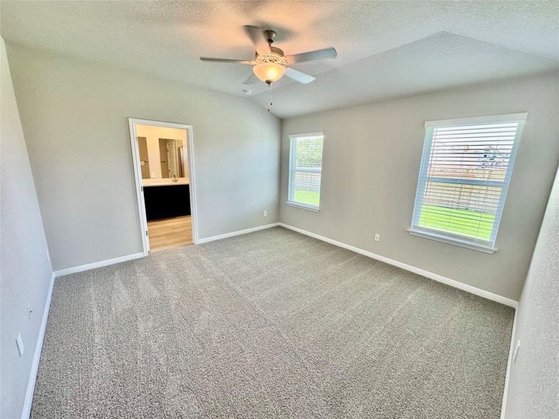 Carpeted empty room featuring a ceiling fan, a textured ceiling, and lofted ceiling Carpeted empty room featuring a ceiling fan, a textured ceiling, and lofted ceiling