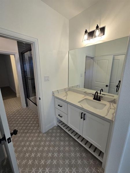 Bathroom with an enclosed shower, vanity, and tile patterned floors