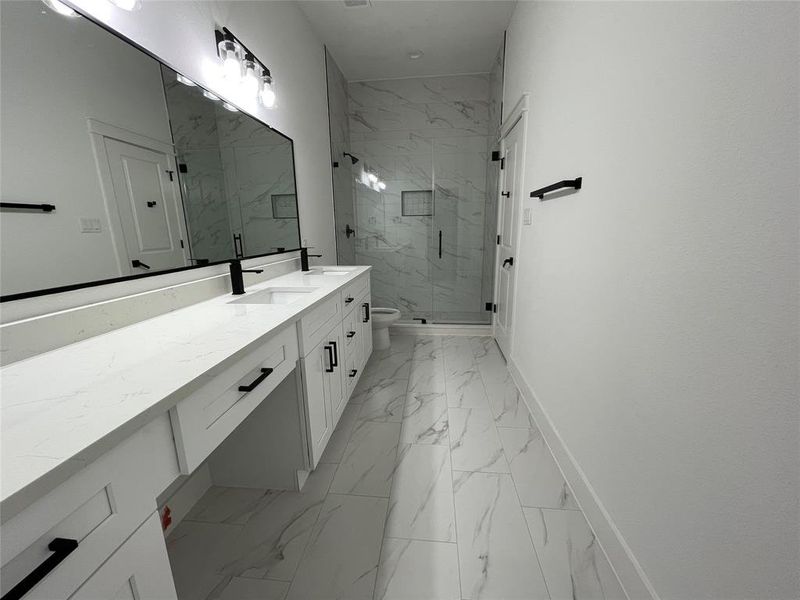 Bathroom featuring vanity, a marble finish shower, and light marble finish floors