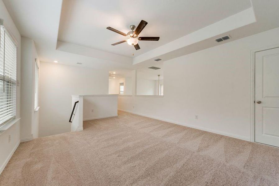 Empty room with a tray ceiling, ceiling fan, and light colored carpet