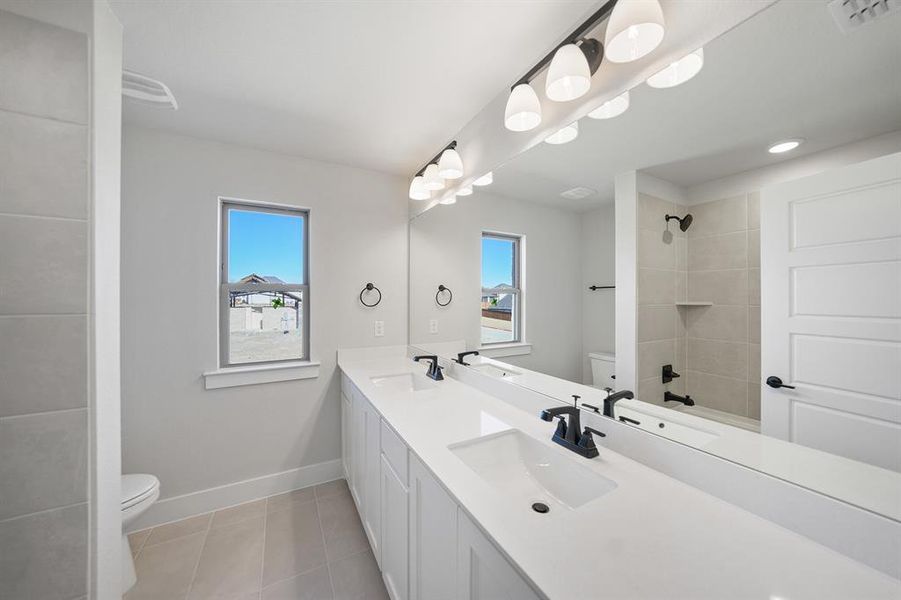 Bathroom featuring double vanity, plenty of natural light, bathtub / shower combination, light tile patterned flooring, and recessed lighting Bathroom featuring double vanity, plenty of natural light, bathtub / shower combination, light tile patterned flooring, and recessed lighting