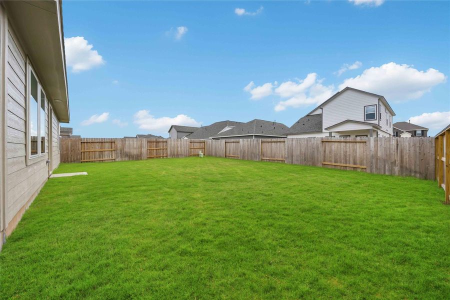 Expansive fenced backyard with lush green lawn, perfect for outdoor activities and privacy.