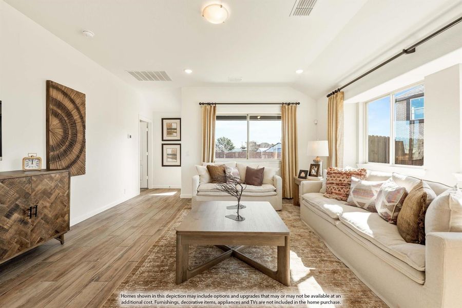 Living room with hardwood floors, cream sofas, wood coffee table, and large windows with gold curtains