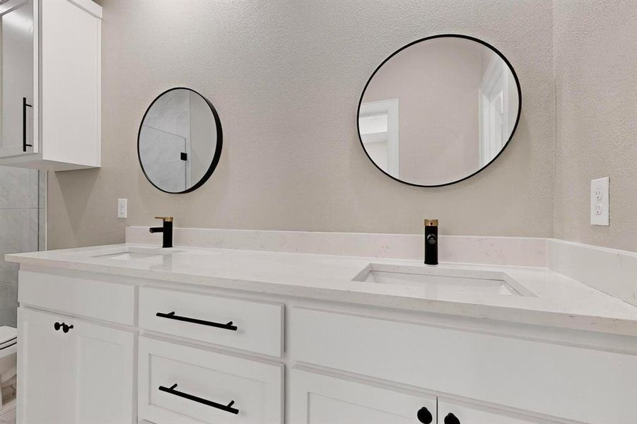 Full bath featuring double vanity and a textured wall Full bath featuring double vanity and a textured wall