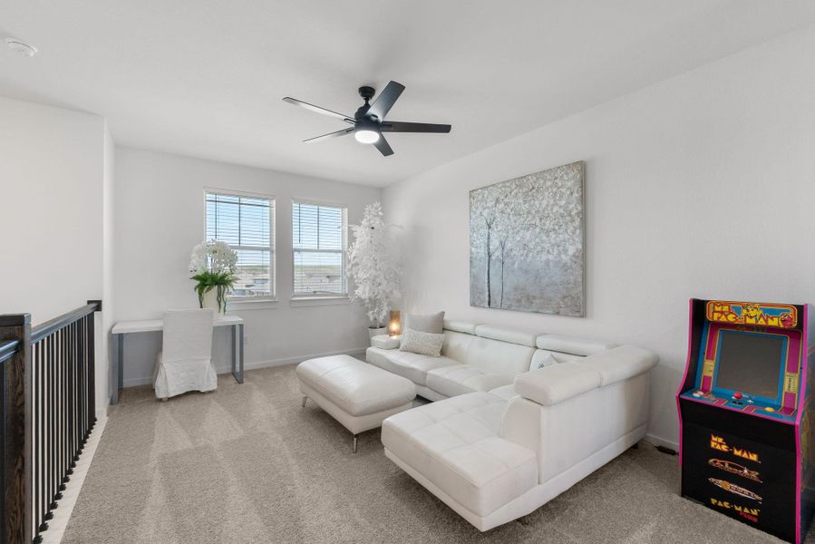 Carpeted living area on the second floor featuring baseboards and ceiling fan