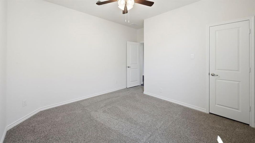 Bright room featuring light gray carpet, white walls, and a ceiling fan with integrated lighting Bright room featuring light gray carpet, white walls, and a ceiling fan with integrated lighting
