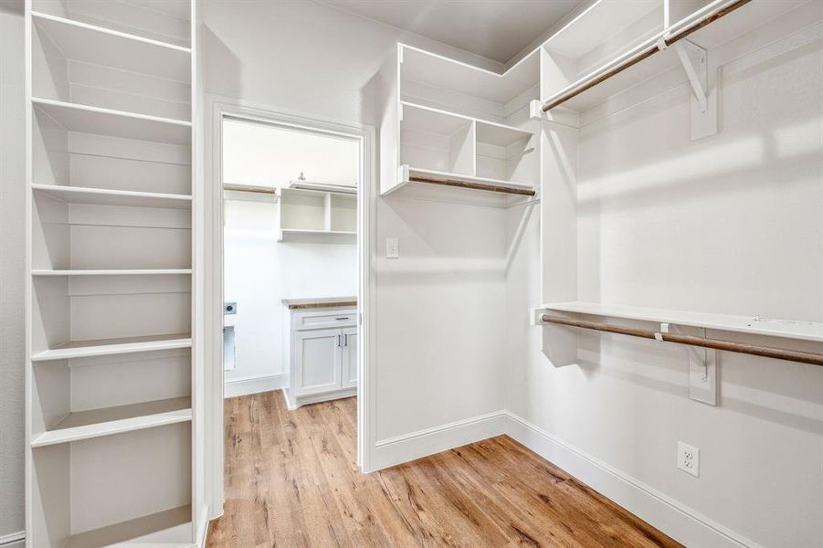 Walk in closet with light hardwood / wood-style floors