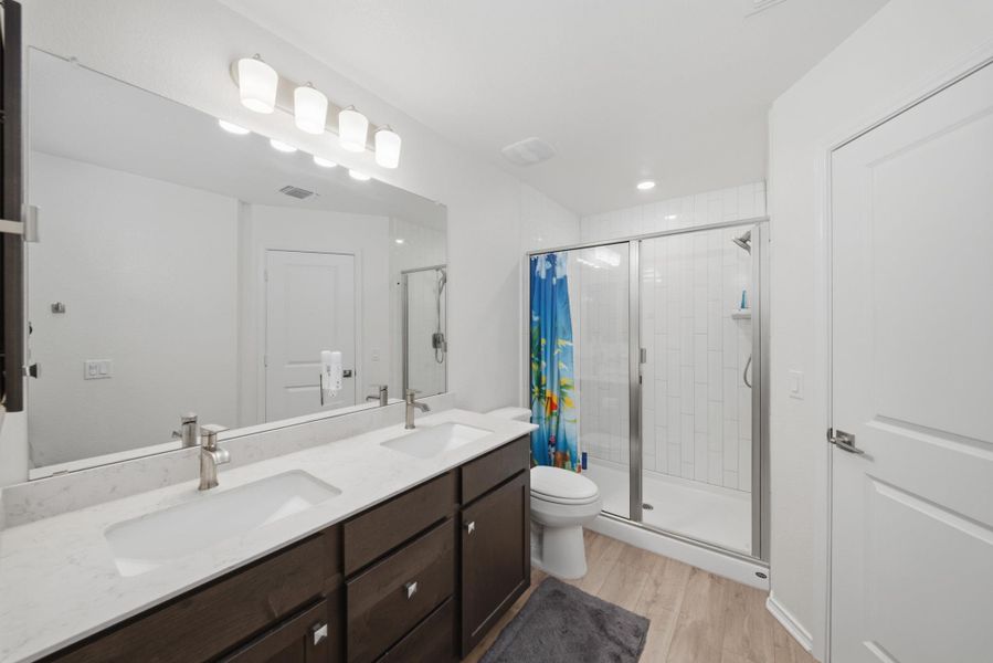 A well-appointed bath features a double vanity and a glass-enclosed walk-in shower. A well-appointed bath features a double vanity and a glass-enclosed walk-in shower.