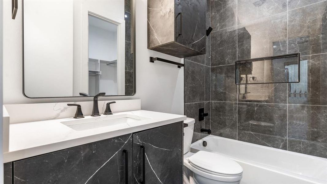 Full bathroom with tiled shower / bath, vanity, and toilet