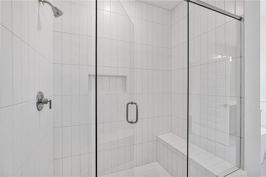 A pristine shower with white tiled walls and hexag A pristine shower with white tiled walls and hexag