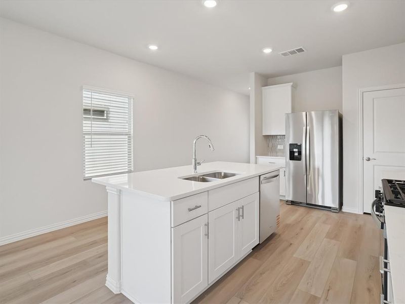 Kitchen featuring stainless steel appliances, white cabinets, light wood finished floors, a kitchen island with sink, and recessed lighting