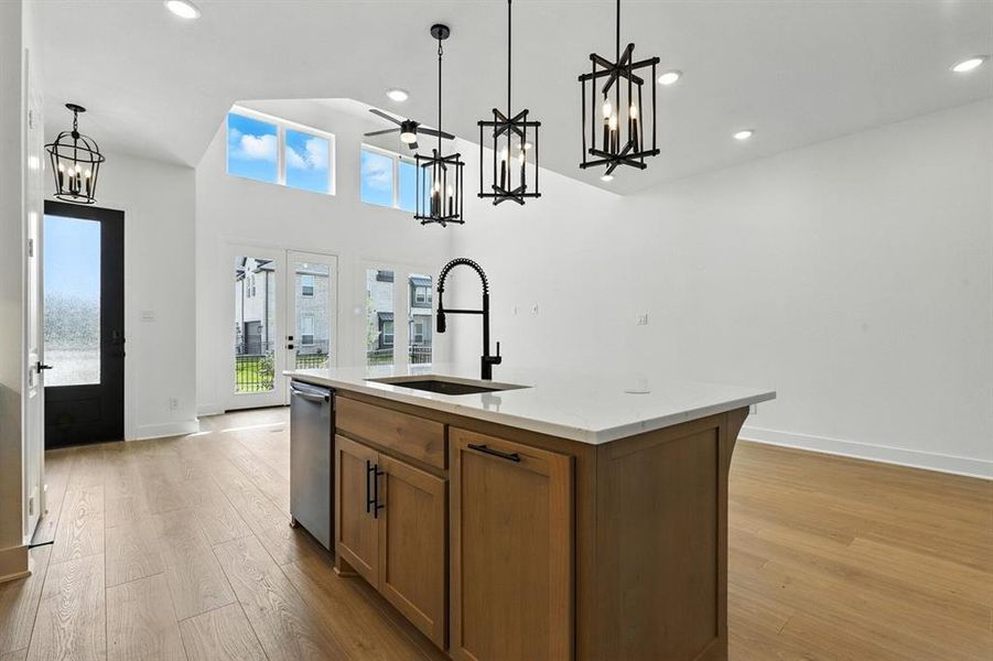 Kitchen with brown cabinets, recessed lighting, a chandelier, pendant lighting, and a center island with sink Kitchen with brown cabinets, recessed lighting, a chandelier, pendant lighting, and a center island with sink