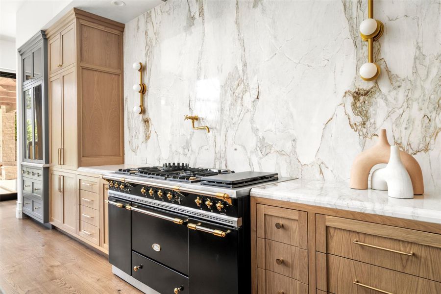 A showstopping Lacanche Cîteaux range anchors the kitchen, framed by custom white oak cabinetry and a dramatic full-height marble slab backsplash. Unlacquered brass accents and sculptural lighting add warmth and refinement to this beautifully tailored culinary space. A showstopping Lacanche Cîteaux range anchors the kitchen, framed by custom white oak cabinetry and a dramatic full-height marble slab backsplash. Unlacquered brass accents and sculptural lighting add warmth and refinement to this beautifully tailored culinary space.