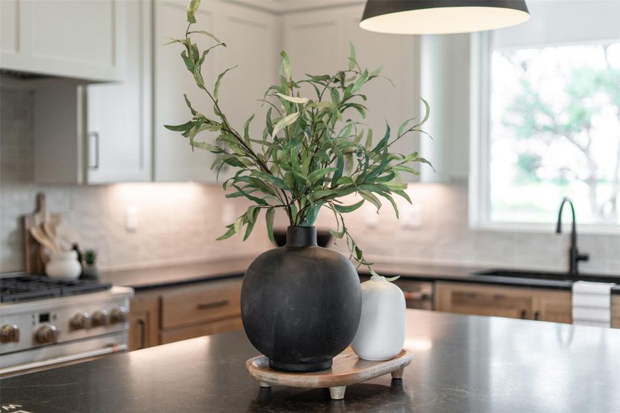 Kitchen view of backsplash, a sink, stainless steel range, and dark countertops Kitchen view of backsplash, a sink, stainless steel range, and dark countertops