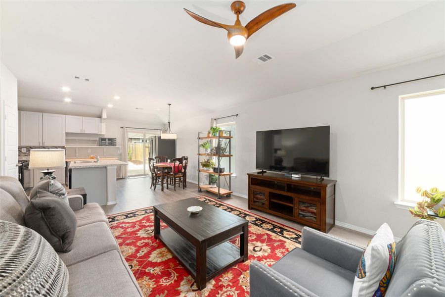 Spacious main living area with large windows and a ceiling fan, creating an open feel that flows naturally into the dining and kitchen areas.