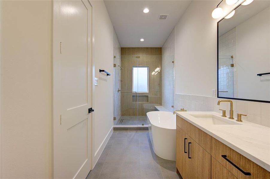 Stunning primary bathroom with clean, contemporary tilework, large shower with sleek linear drain, and soaking tub.