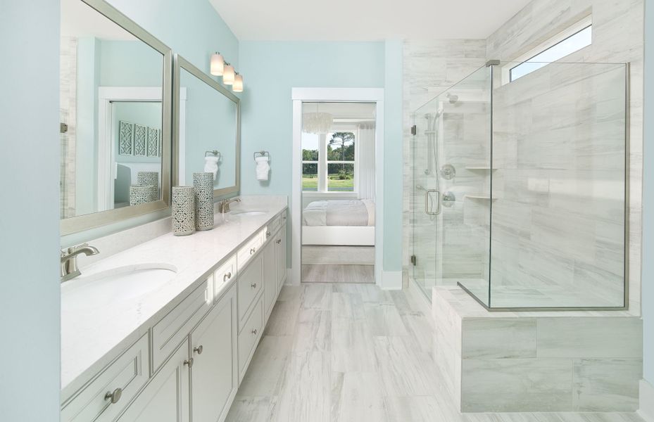 Owner's bathroom with a frameless walk-in shower and dual sink vanity.