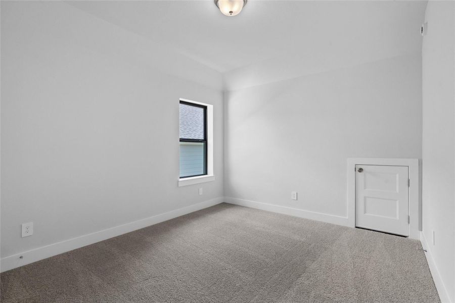 Step into this bright and airy secondary bedroom! It offers a tranquil space to unwind. The large window illuminates the room's sloped ceiling and neutral tones, creating a cheerful and airy environment.