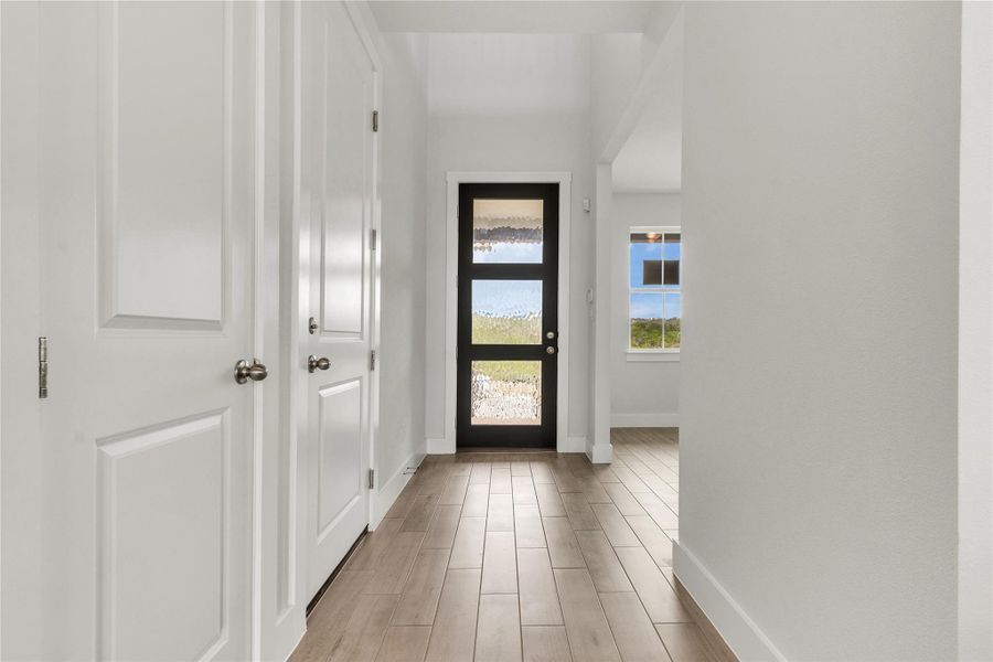 A welcoming entryway with sleek wood flooring and a modern door awaits residents.