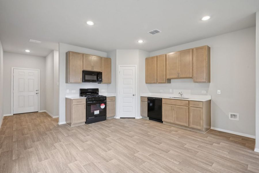 Image of a kitchen with brown cabinets, black appliances and a corner pantry