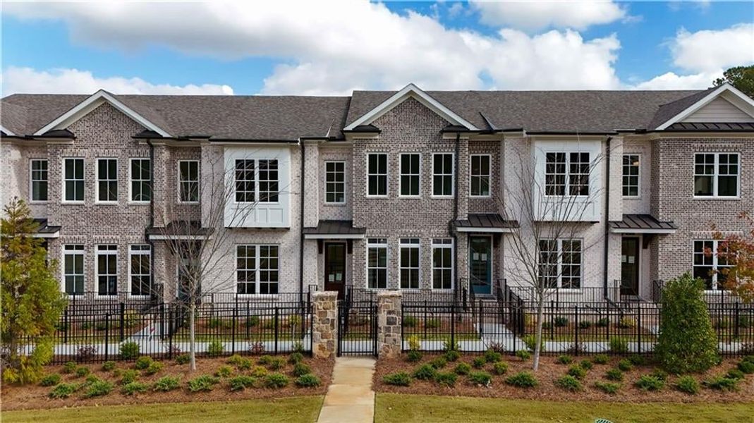 Townhome / multi-family property with brick siding and a fenced front yard